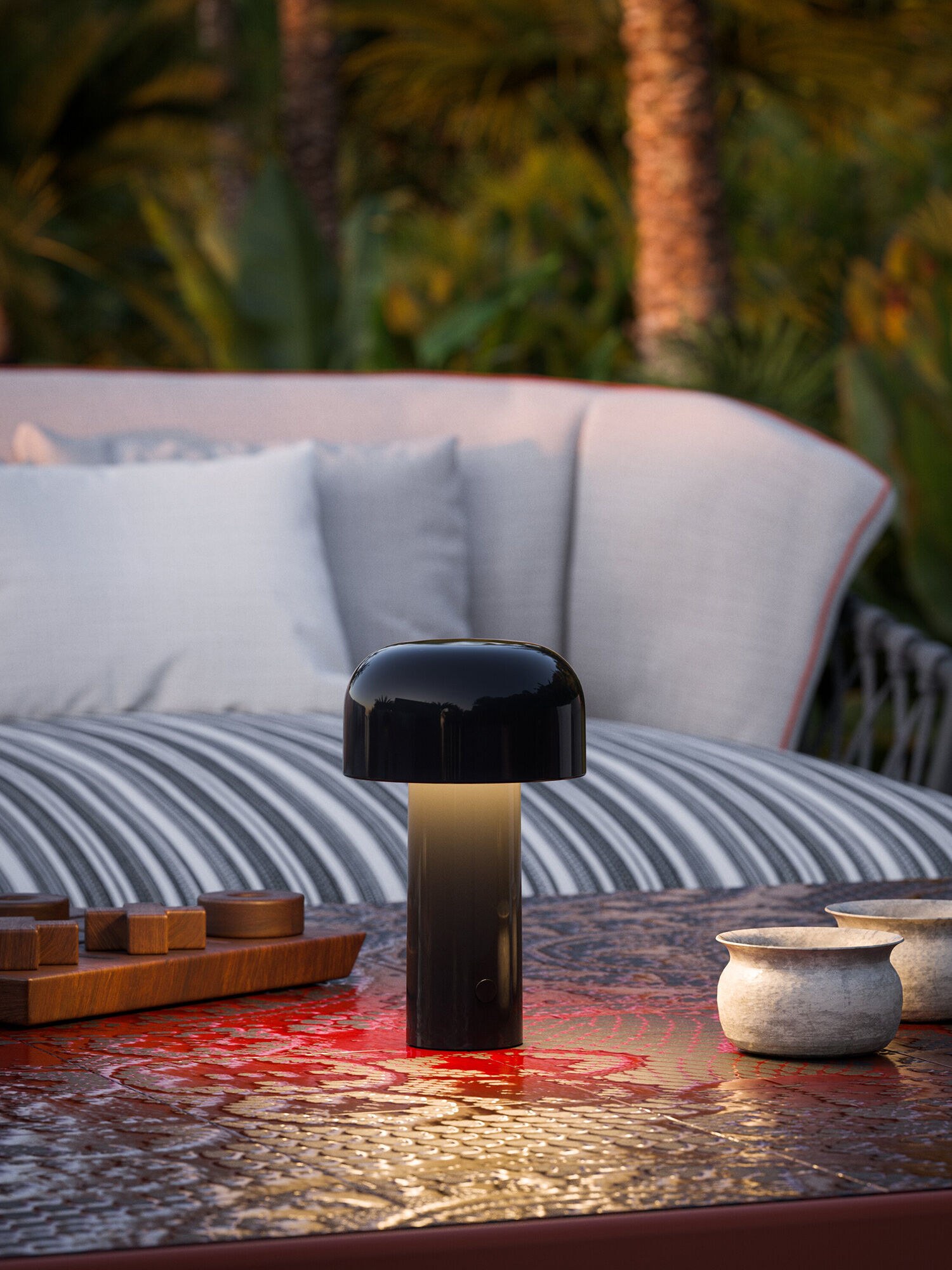Portable lamp in black on an outdoor table in front of a sofa