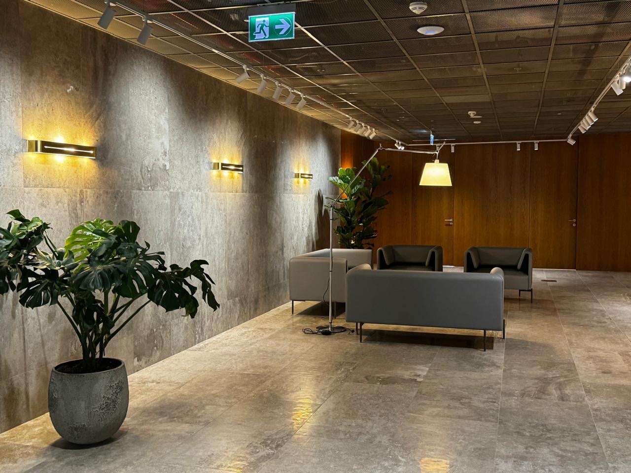 Corridor with a stone-textured wall, gold wall lights and grey sofas