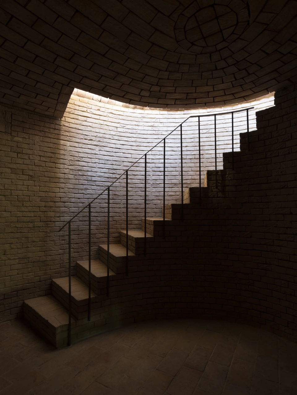 The brick stair, lit from the vault above