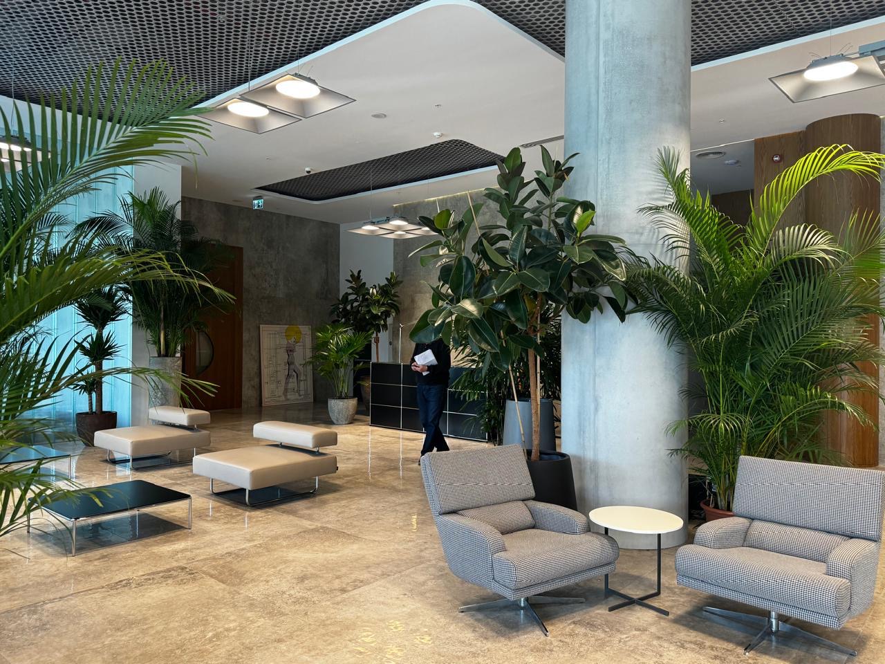 Lobby with a concrete column, grey armchairs and plants