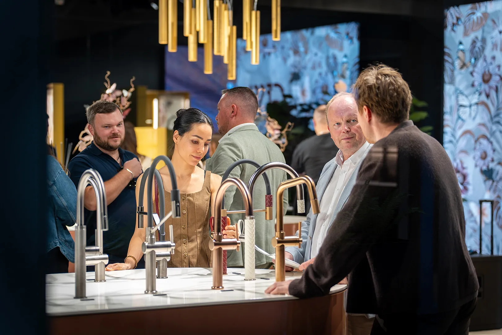 Visitors looking at kitchen taps in steel, copper and gold finishes